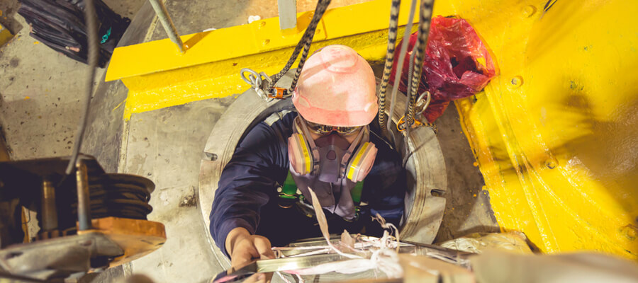 top view of a male worker climbing in or out of a confined space