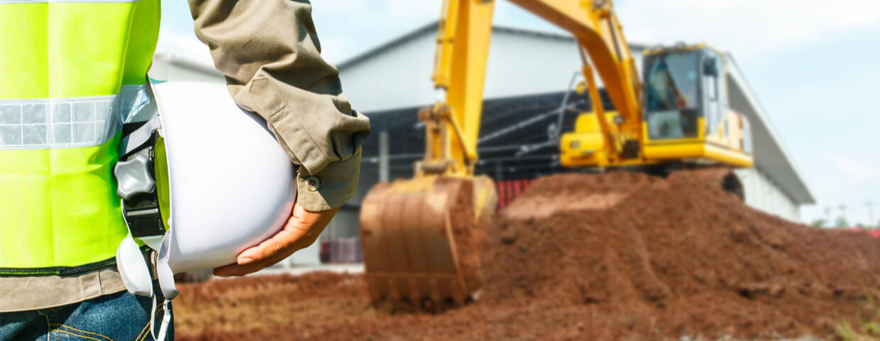 Engineer with hard hat and excavator machine at construction site