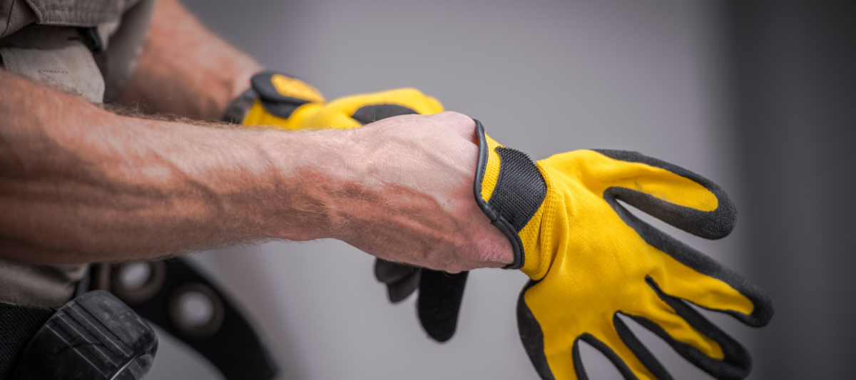 close up of worker putting on gloves or safety equipment, safety training