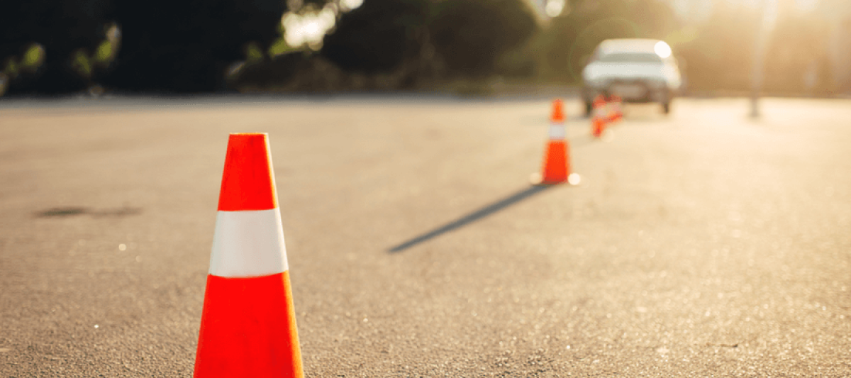 Traffic cone in focus with more cones and a car in the background blurred