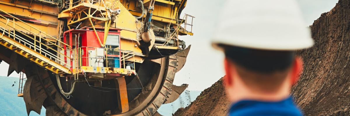 Mining Safety Training concept, worker or employee with hard hat standing near mining equipment