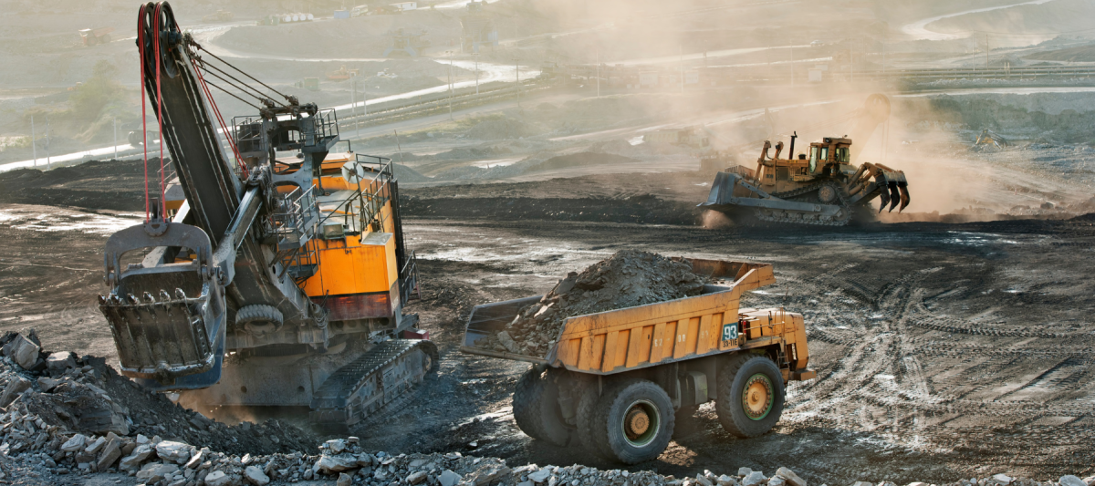 wide angle of a mining operation, surface mining safety with loaders, dump trucks, and graders with a conveyor belt running rocks or materials through the mining process