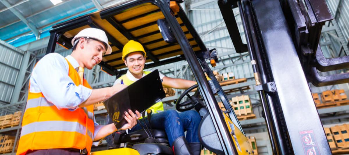 forklift driver discussing checklist with foreman in warehouse