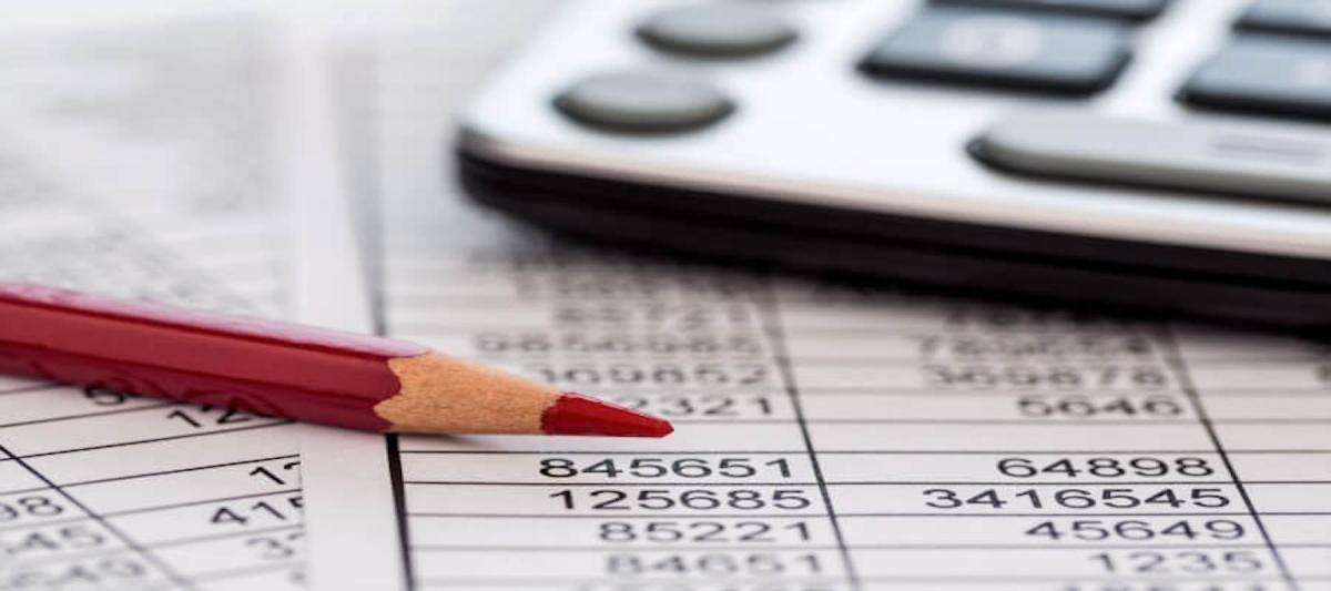 red pencil and calculator on a balance sheet